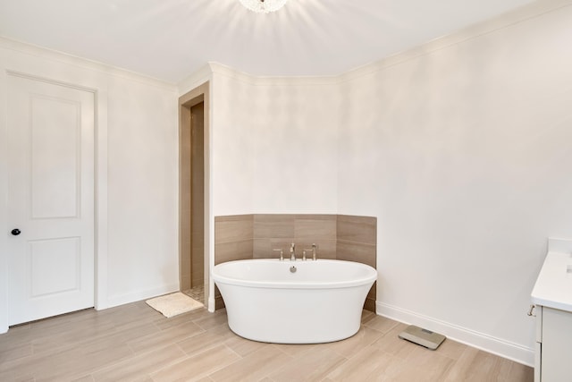 bathroom with a freestanding bath, wood finish floors, vanity, and baseboards