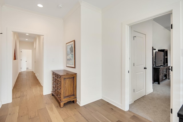 hallway featuring light wood finished floors, baseboards, crown molding, and recessed lighting