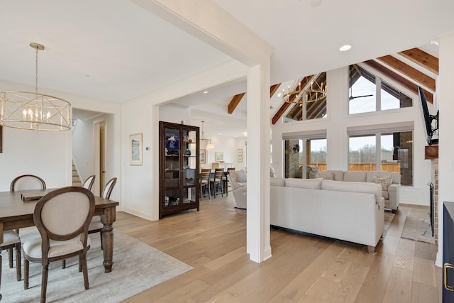 dining space with beamed ceiling, light wood-style flooring, and an inviting chandelier