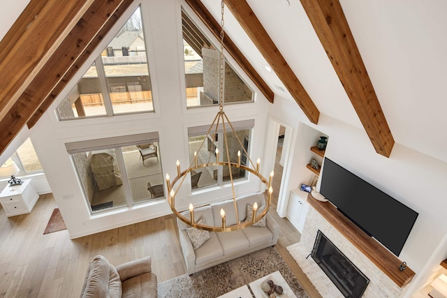 living area with vaulted ceiling with beams, an inviting chandelier, a healthy amount of sunlight, and wood finished floors