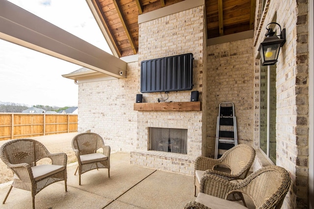 view of patio with an outdoor brick fireplace and fence