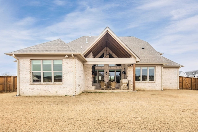 back of house featuring a patio, brick siding, roof with shingles, and a fenced backyard