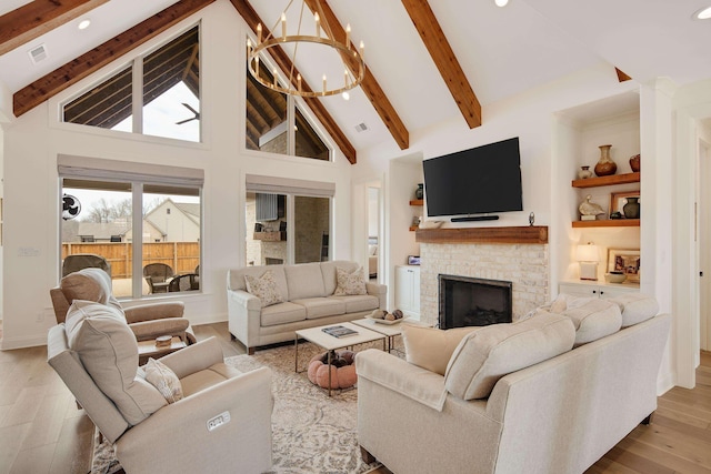 living area with a chandelier, high vaulted ceiling, built in shelves, a fireplace, and wood finished floors