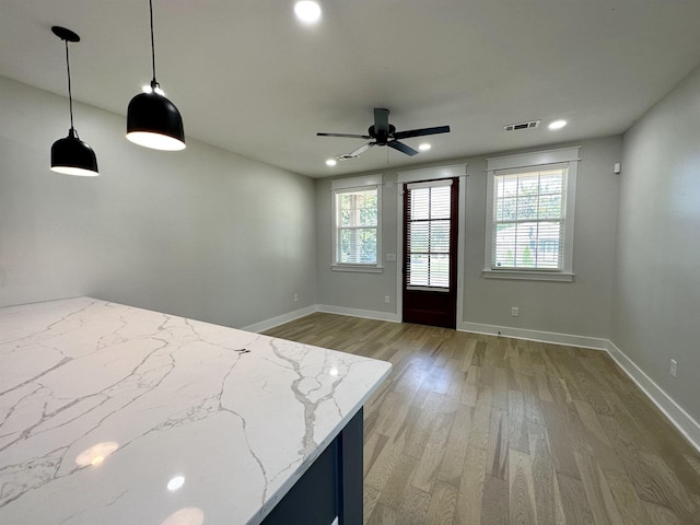 interior space with light wood-type flooring, baseboards, multiple windows, and visible vents