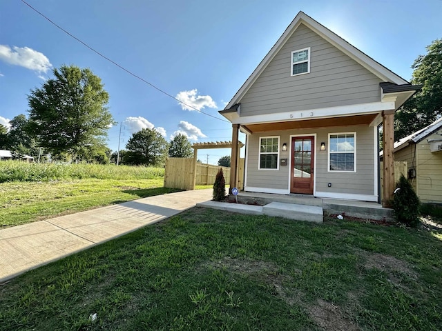 rear view of house featuring a porch, a lawn, and fence