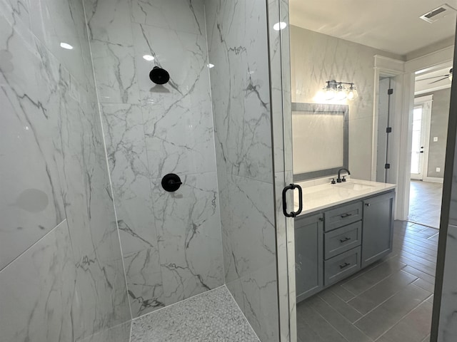 full bath with visible vents, vanity, and a marble finish shower