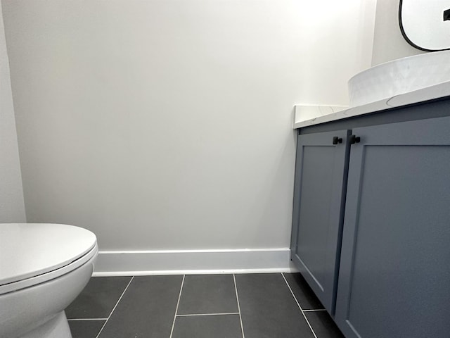 half bath featuring baseboards, vanity, toilet, and tile patterned floors