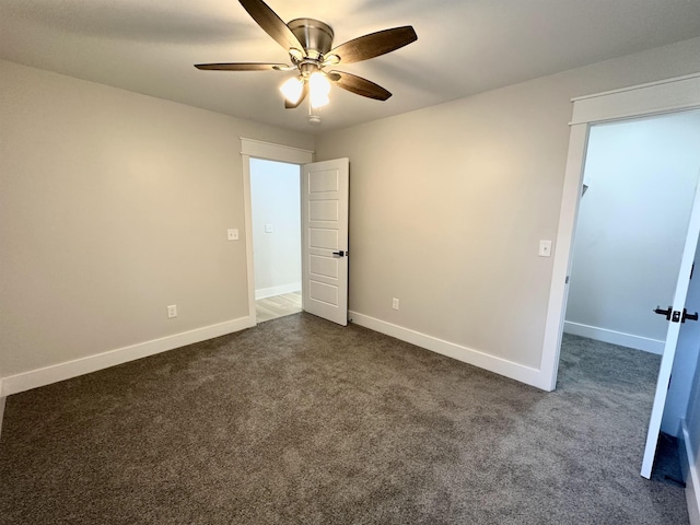 unfurnished bedroom with ceiling fan, dark carpet, and baseboards