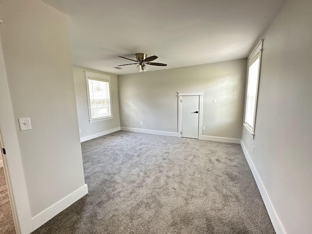 carpeted spare room with ceiling fan and baseboards