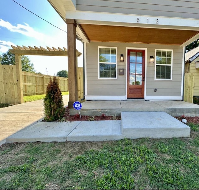 doorway to property with fence and a pergola