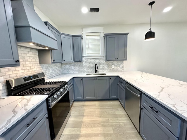 kitchen with stainless steel appliances, custom range hood, a sink, and light stone counters