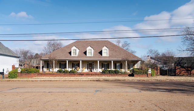 cape cod-style house featuring covered porch and roof with shingles