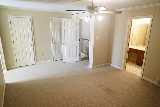 unfurnished bedroom with light carpet, two closets, crown molding, and ensuite bathroom