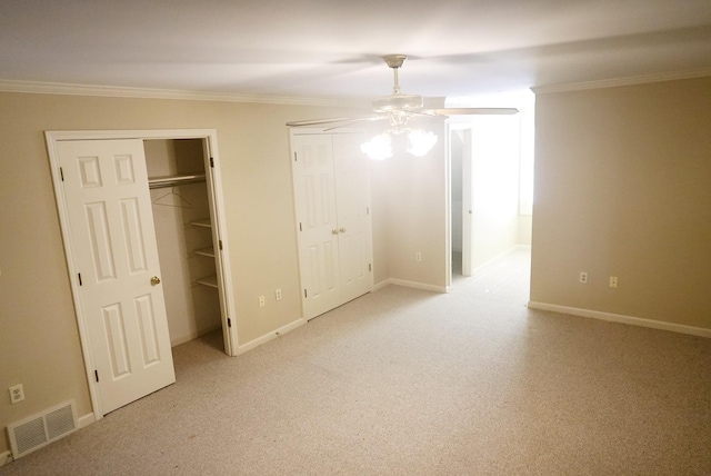 unfurnished bedroom with ornamental molding, visible vents, and two closets