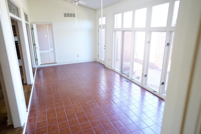 spare room featuring high vaulted ceiling, dark tile patterned floors, visible vents, baseboards, and a ceiling fan