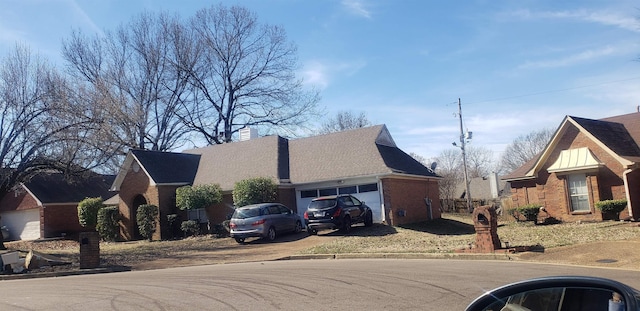 view of property exterior with an attached garage, driveway, a chimney, and brick siding