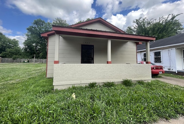 view of front of home featuring covered porch, a front yard, and fence