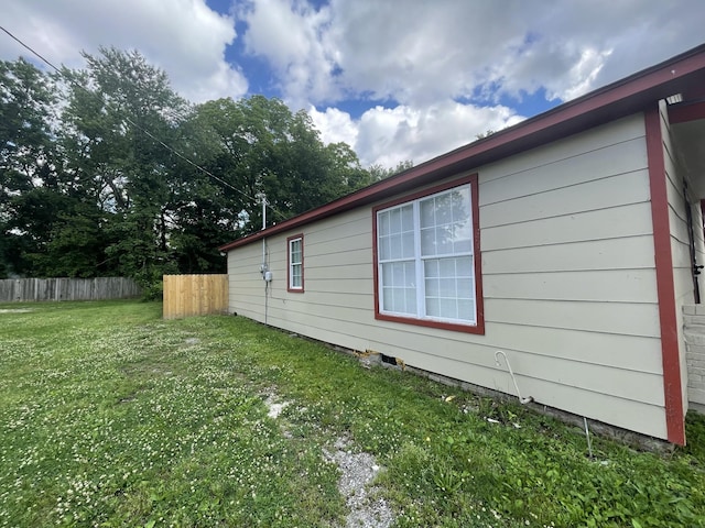 view of side of home with a yard and fence