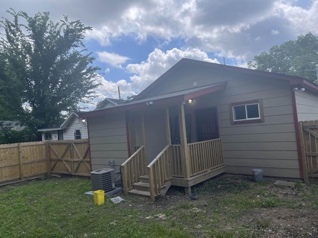 rear view of property with a yard, cooling unit, a gate, and fence