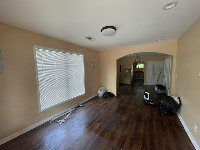 exercise room featuring baseboards, visible vents, arched walkways, and wood finished floors