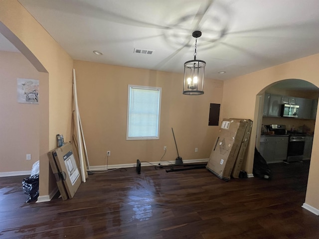 unfurnished dining area with arched walkways, visible vents, baseboards, electric panel, and dark wood-style floors