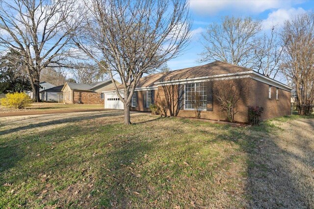 ranch-style house featuring brick siding, an attached garage, and a front lawn