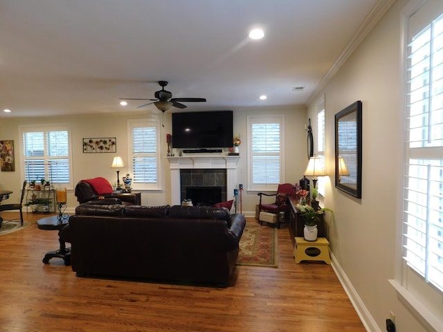 living area with a tile fireplace, recessed lighting, baseboards, and wood finished floors