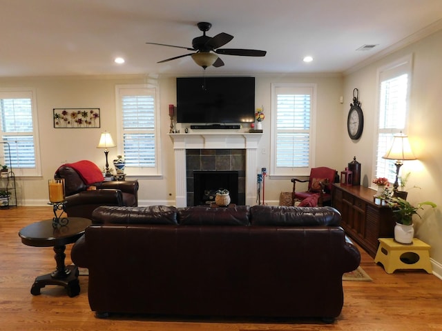 living area featuring visible vents, crown molding, a fireplace, and wood finished floors