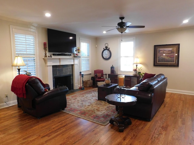 living room featuring ornamental molding, a fireplace, baseboards, and wood finished floors