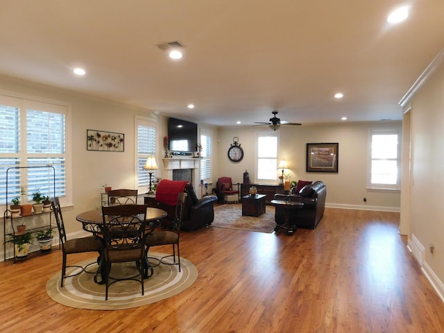 living room featuring recessed lighting, visible vents, ornamental molding, wood finished floors, and a tile fireplace