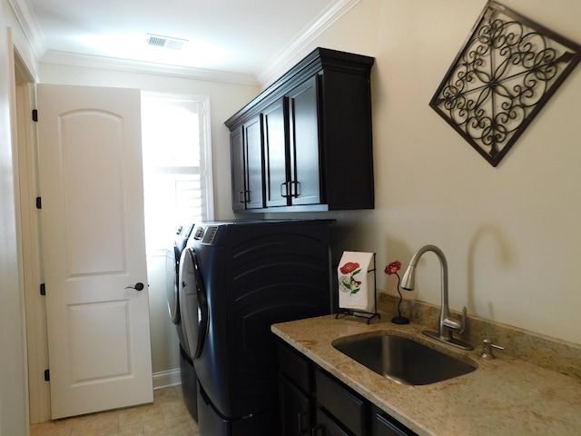 clothes washing area featuring washing machine and clothes dryer, cabinet space, visible vents, ornamental molding, and a sink