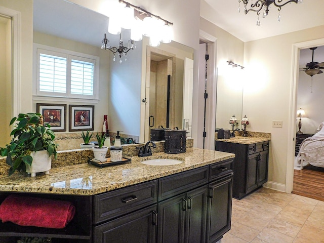 ensuite bathroom featuring connected bathroom, vanity, baseboards, and ceiling fan with notable chandelier