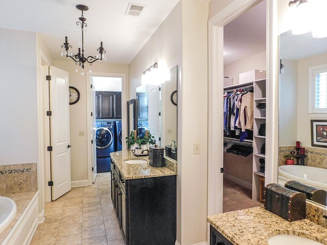 bathroom with a garden tub, visible vents, washer / clothes dryer, and two vanities