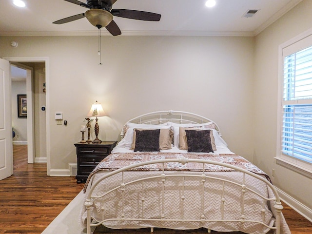 bedroom with baseboards, wood finished floors, visible vents, and crown molding