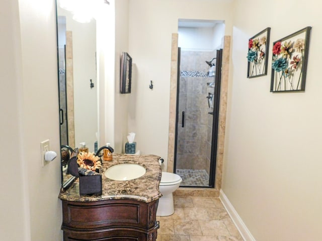 bathroom featuring a stall shower, toilet, vanity, and baseboards