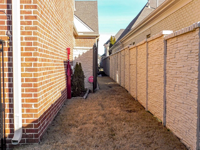 view of property exterior featuring fence and brick siding