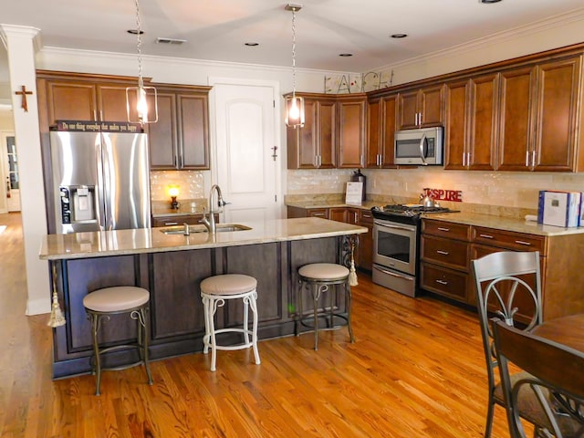 kitchen with stainless steel appliances, visible vents, hanging light fixtures, a sink, and wood finished floors