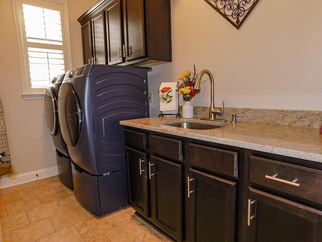 laundry area with washer and clothes dryer, a sink, cabinet space, and baseboards