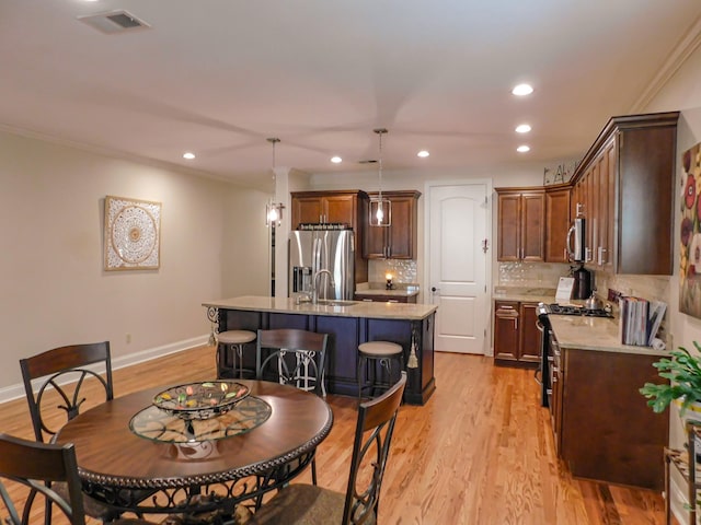 dining area featuring ornamental molding, baseboards, visible vents, and light wood finished floors