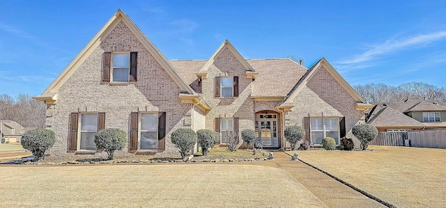 view of front of property featuring brick siding, fence, and a front lawn