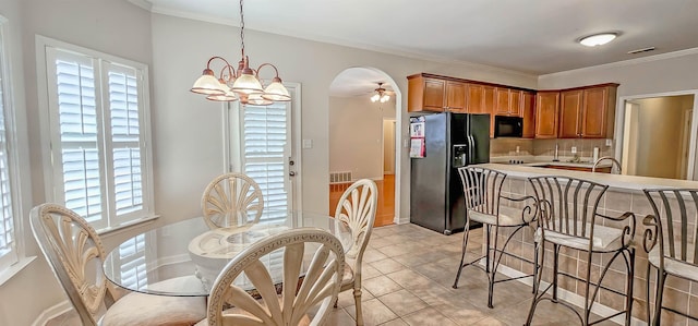 kitchen with arched walkways, brown cabinets, a ceiling fan, black appliances, and a kitchen breakfast bar