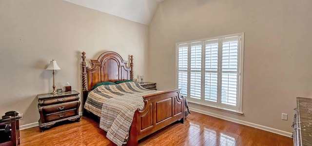 bedroom featuring lofted ceiling, wood finished floors, and baseboards