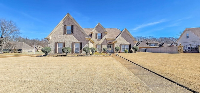 view of front of home featuring brick siding, a front yard, and fence