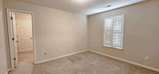 carpeted empty room featuring baseboards, visible vents, and a textured ceiling