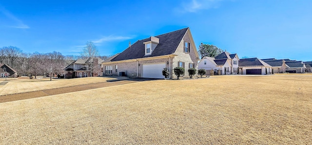 view of side of home with brick siding, a lawn, a garage, a residential view, and driveway