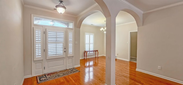 entryway with arched walkways, crown molding, baseboards, and wood finished floors