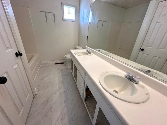 full bath featuring double vanity, baseboards, toilet, marble finish floor, and a sink