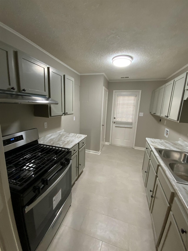 kitchen with visible vents, gas range, light countertops, under cabinet range hood, and a sink