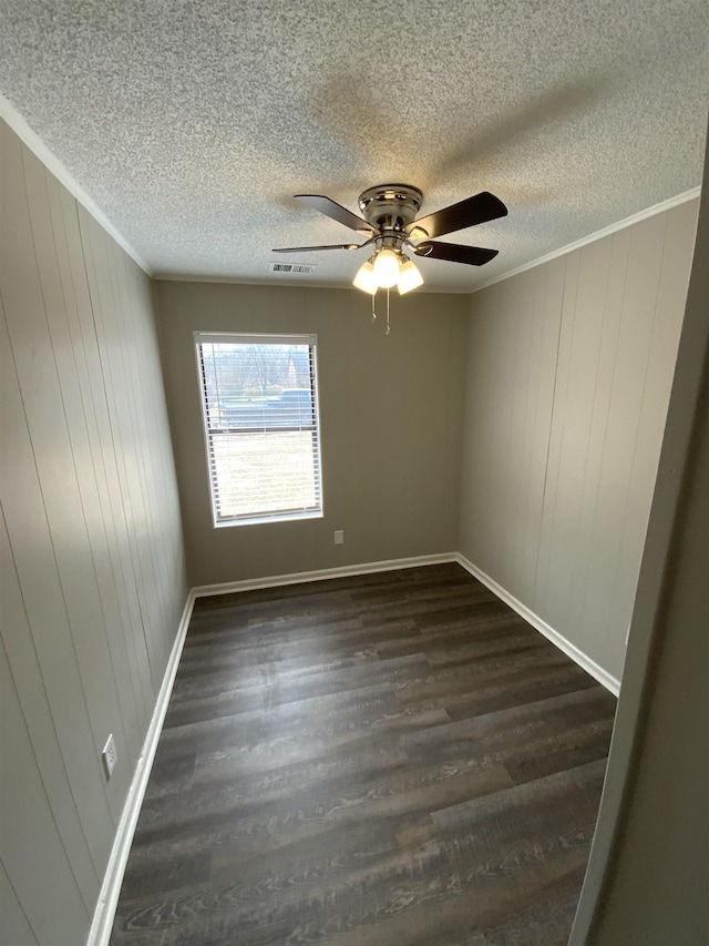 unfurnished room with ceiling fan, a textured ceiling, visible vents, dark wood finished floors, and crown molding