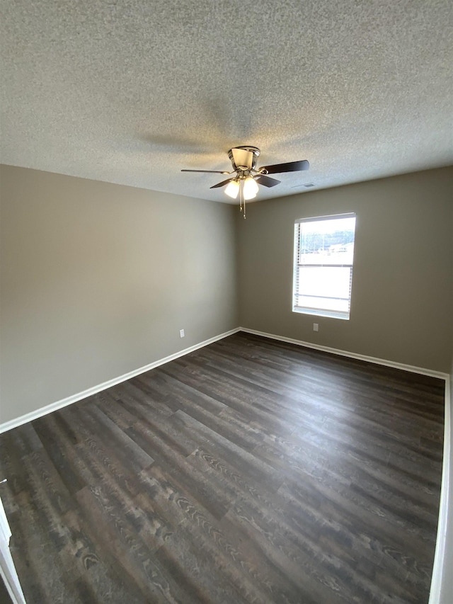 spare room featuring dark wood finished floors, a textured ceiling, baseboards, and ceiling fan